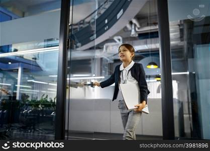 Little businesswoman enter conference room. Girl holding document folder in hand with smile on face. Business girl entering conference room with smile