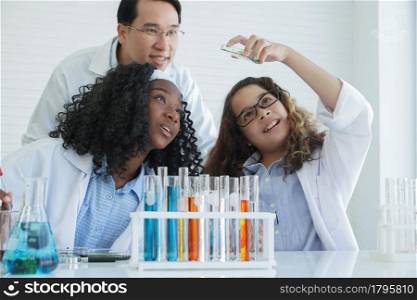 Little Caucasian and African scientist kids learning chemistry in school laboratory. Asian teacher man and adorable girls doing chemical science experiment in laboratory. white back ground