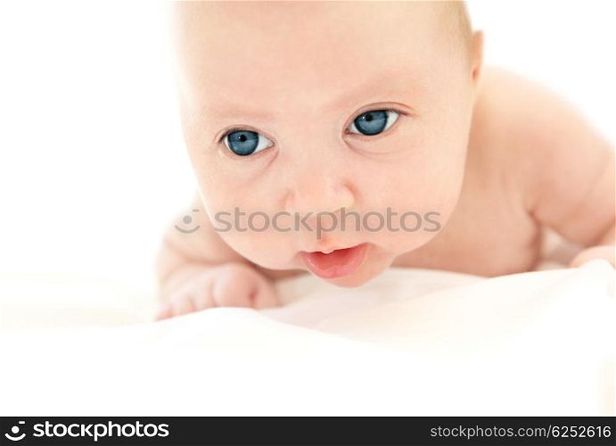 Little Caucasian baby lying in the bed isolated on white background with copyspace