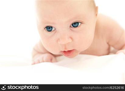 Little Caucasian baby lying in the bed isolated on white background with copyspace