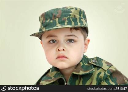 little Caucasian boy in military clothes isolated on light background