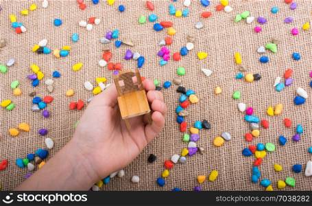 Little chair in hand amid colorful pebbles on canvas