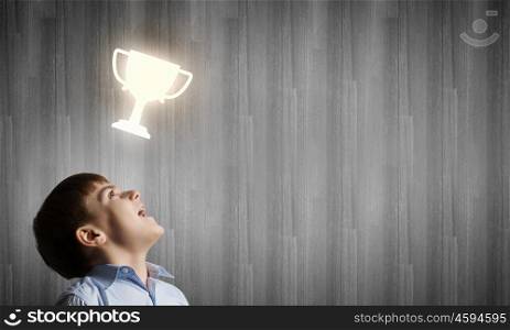 Little champion. Cute boy of school age and cup above his head