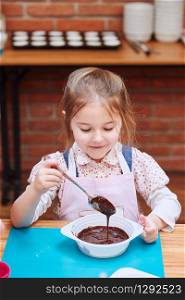Little chef stirring hot melted chocolate with cocoa. Kid taking part in baking workshop. Baking classes for children, aspiring little chefs. Learning to cook. Combining and stirring prepared ingredients. Real people, authentic situations