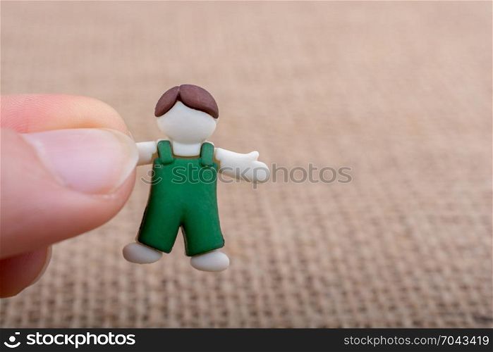 Little child figurine in hand on a brown backgorund