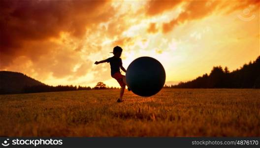 Little child playing football on the meadow