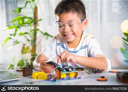 Little child remotely learn online with car toy before sent code, Asian kid boy plugging energy and signal cable to sensor chip with Arduino robot car, STEAM education AI technology course learning