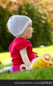 little child sitting on a grass at the park