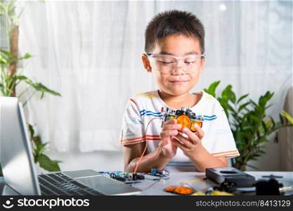 Little child trying assemble build wheel to car toy, Asian kid boy assembling wheel into Arduino robot car homework, creating electronic AI technology workshop online school lesson