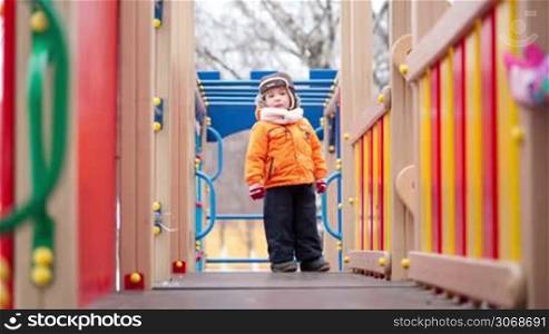 Little children in warm cloths having fun on playground equipment. Outdoor activity for children