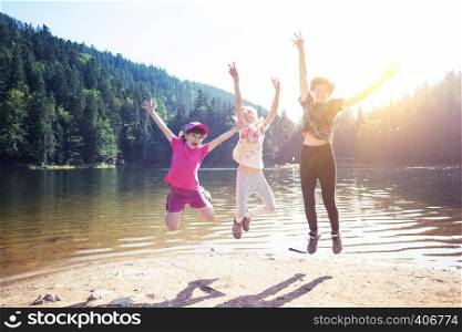 little children on a hike. Fun happy children jumping on the shore of a mountain lake synevyr.