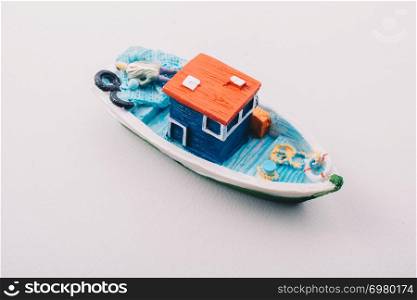 Little colorful model fishing boat placed on white