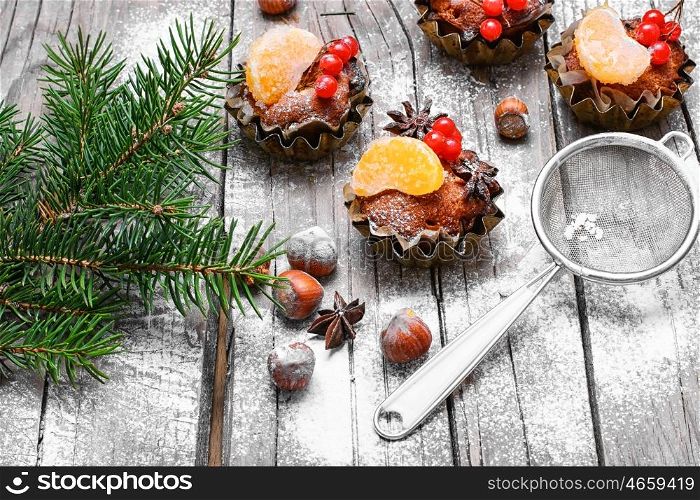 little cupcakes in tins ,decorated with berries and a slice of tangerine