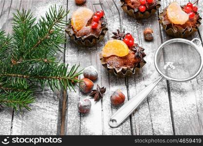 little cupcakes in tins ,decorated with berries and a slice of tangerine