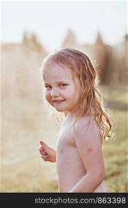 Little cute adorable girl enjoying a cool water sprayed by her mother during hot summer day in backyard. Candid people, real moments, authentic situations
