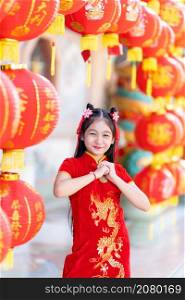 little Cute Asian girl wearing traditional Chinese cheongsam red with paper lanterns with the Chinese alphabet Blessings written on it Is a Fortune blessing compliment decoration for Chinese New Year