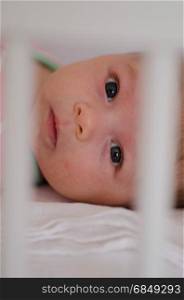 little cute baby girl playing in a cot