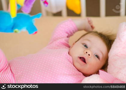 little cute baby girl playing in a cot