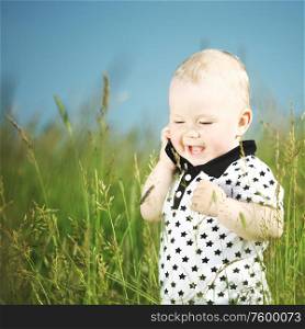 Little cute boy in green grass meadow call by phone. Boy in grass call by phone