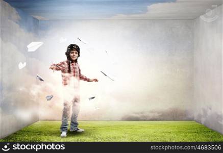 Little cute boy in pilot helmet and paper airplanes flying around