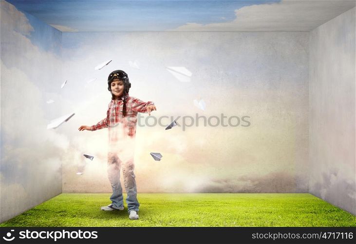 Little cute boy in pilot helmet and paper airplanes flying around