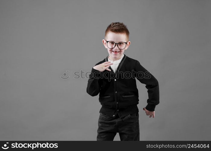 Little cute boy with glasses is smiling and having fun isolated on grey background. happy childhood. copy space.. Little cute boy with glasses is smiling and having fun isolated on grey background. happy childhood. copy space