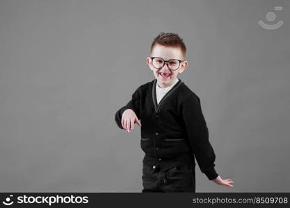 Little cute boy with glasses is smiling and having fun isolated on grey background. happy childhood. copy space.. Little cute boy with glasses is smiling and having fun isolated on grey background. happy childhood. copy space