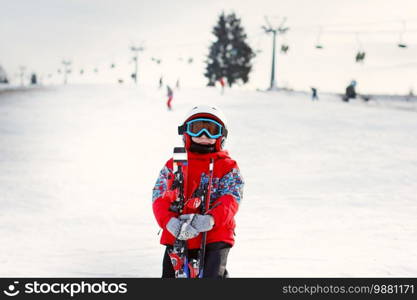 Little cute boy with skis and a ski outfit. Little skier in the ski resort