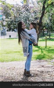 Little cute child baby hugging mom, embrace with happy pretty woman in park.