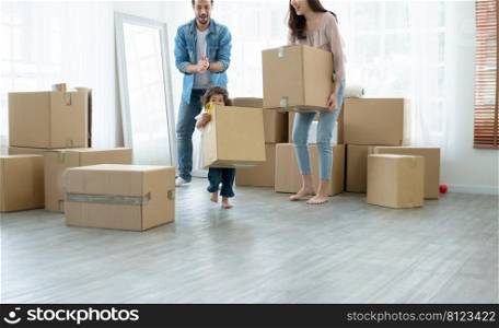Little cute daughter helping mother and father to move big cardboard box while father clap his hands to cheer up. Young mixed race family and kid preparing stuff for move to new house together