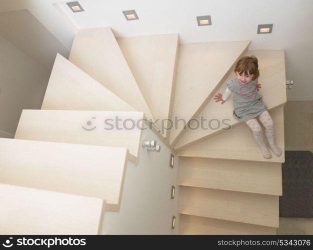 little cute girl enjoying on the stairs in a modern living room of her luxury home