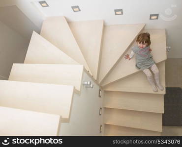 little cute girl enjoying on the stairs in a modern living room of her luxury home