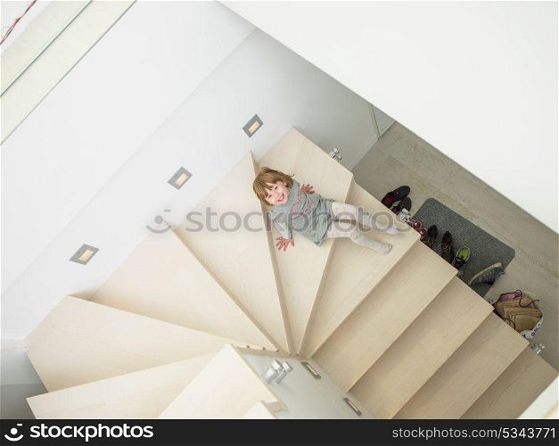 little cute girl enjoying on the stairs in a modern living room of her luxury home