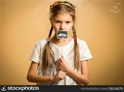 Little cute girl holding funny decorative mustaches