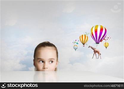 Little cute girl looking from under the table. Giraffe flying on balloons