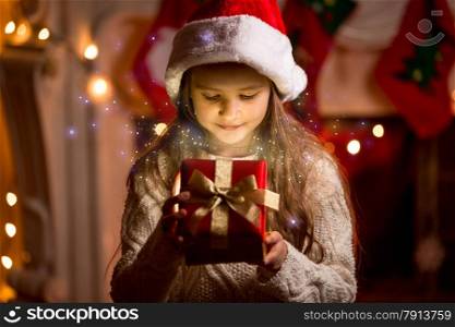 Little cute girl looking inside of glowing Christmas present box