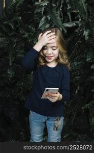 little cute girl looking smart phone putting hand her head