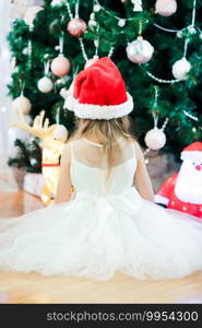 Little cute girl near christmas tree on christmas eve. Little cute girl near christmas tree. Children under Christmas tree with gift boxes.