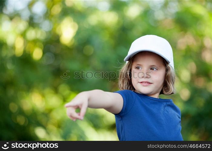 Little cute girl with a cap in the park indicating the direction