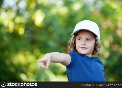 Little cute girl with a cap in the park indicating the direction