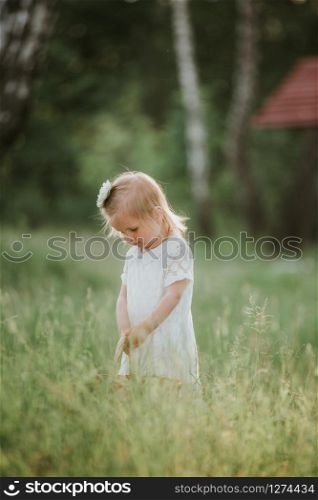 little cute girl with basket in white dress have fun in the park.. little cute girl with basket in white dress have fun in the park