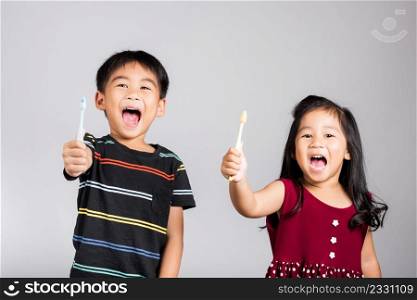 Little cute kid boy and girl 3-6 years old show brush teeth and smile in studio shot isolated on white background, Asian children holding toothbrush in mouth by himself, Dental hygiene healthy concept