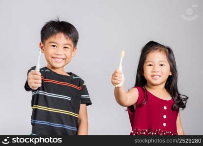 Little cute kid boy and girl 3-6 years old show brush teeth and smile in studio shot isolated on white background, Asian children holding toothbrush in mouth by himself, Dental hygiene healthy concept