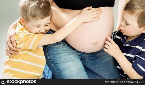 Little cute sons stroking pregnant mother's belly