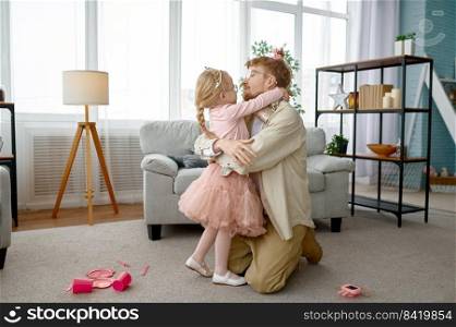 Little daughter hugging and kissing happy smiling father over home living room interior, cute family portrait. Little daughter kissing happy smiling father