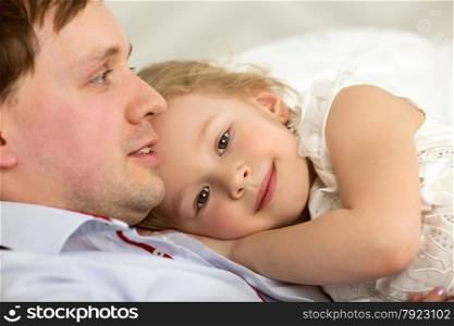 Little daughter lying on fathers chest. She showing her devotion to dear dad. Lovely girl close to beloved father