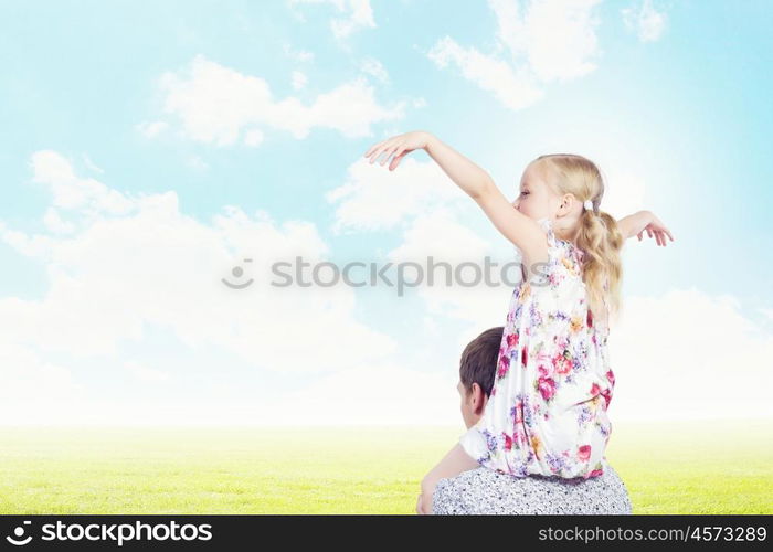 Little daughter sitting on father's shoulders. Parenting concept