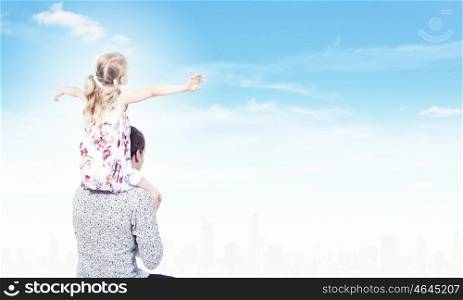 Little daughter sitting on father's shoulders. Parenting concept