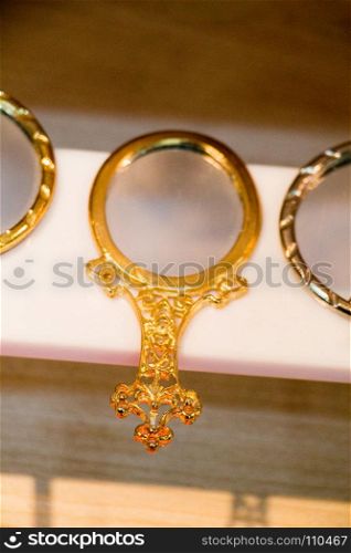Little decorative gold color hand mirror on a shelf