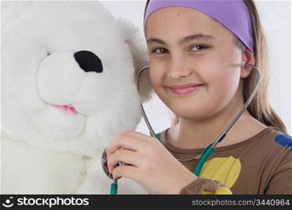 Little doctor smiling and examining her teddy